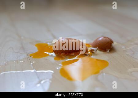 Broken raw egg spilled on a wooden parquet floor Stock Photo