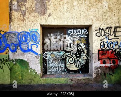 Graffiti Covered Window in Weathered Urban Wall Stock Photo