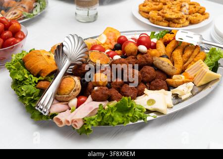 Generous catering platter filled with meatballs, sausages, cheese, ham, stuffed mushrooms, breaded snacks, cherry tomatoes, mozzarella, olives and fre Stock Photo