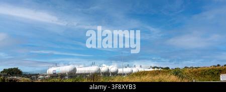 Large white LPG storage tanks at the Flogas marine terminal in Drogheda stand under a blue sky with light clouds. Stock Photo