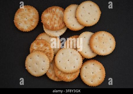 Round salted crackers on a black background. Stock Photo