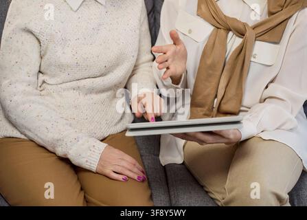 Senior woman guided by consultant using tablet for online support and planning Stock Photo