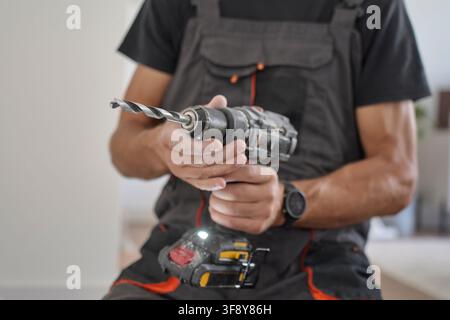 Worker holding a cordless drill with drill bit indoors. Concept of home renovation, construction and DIY improvement work Stock Photo