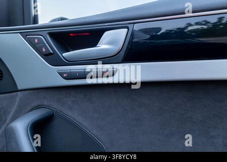 Vinkovci, Croatia - May 15.2026:Close-up of a modern luxury car door interior panel featuring a silver handle, memory seat buttons, soft fabric trim a Stock Photo