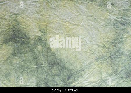 Muted green handmade paper featuring visible fibrous strands and irregular layered markings, creating an earthy organic textured background. Stock Photo