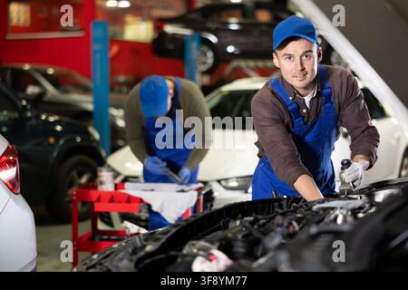 Professional mechanic man in uniform repairing car in auto repair garage Stock Photo