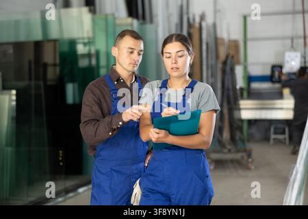 Two glass workshop workers discussing documents Stock Photo