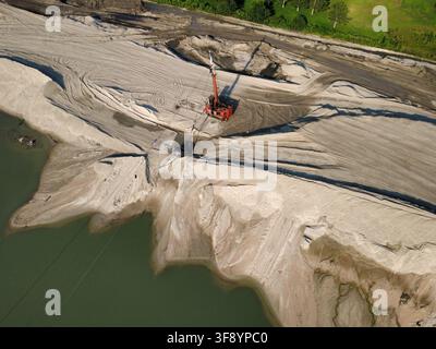 Aerial view of dredging and earthmoving operations at a construction site with excavated sand, embankment construction, and water basin. Stock Photo
