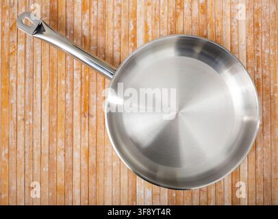 New steel frying pan on wooden background close up Stock Photo