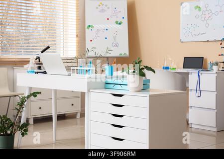 Modern science laboratory interior with microscope laptops test tubes and chemical formulas on whiteboards for education and research Stock Photo