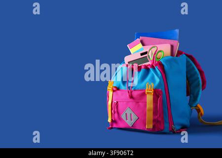 Stylish school backpack with different stationery on blue background Stock Photo