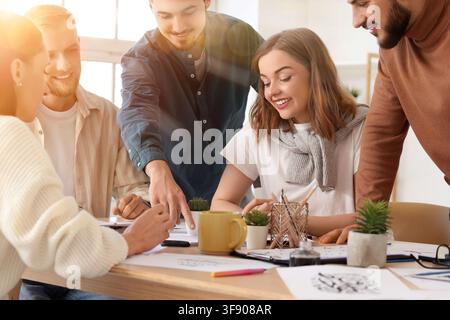 Creative business team collaborating on a design project in a modern office, discussing ideas and pointing at documents, Young professionals are engag Stock Photo