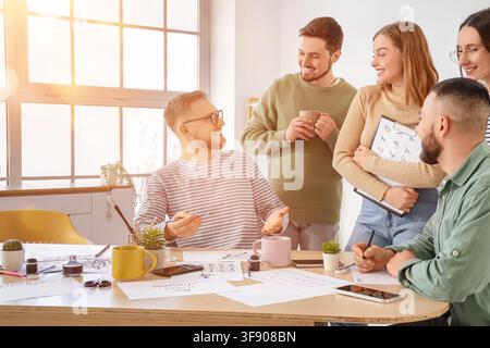 Group of young designers collaborating on a creative project, discussing calligraphy and lettering art in a bright studio Stock Photo