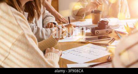 Creative calligraphy workshop with students practicing lettering and design skills on paper at a wooden table, Multiple individuals are engaged in wri Stock Photo