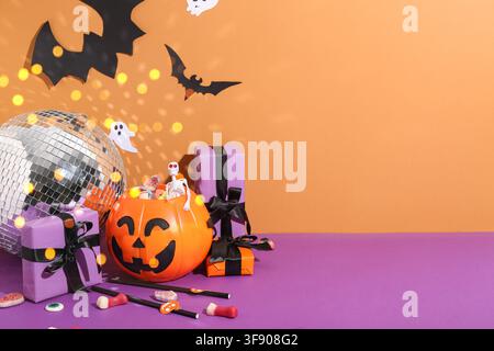 Halloween party decorations with disco ball pumpkin candy bucket skeleton and ghost cutouts on orange and purple background Stock Photo
