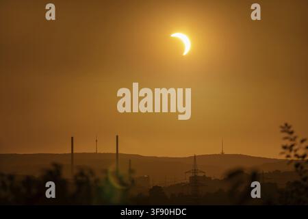 12 August 2026, a partial solar eclipse shines over the city skyline and TV tower in an orange glowing sky, Stuttgart, Germany Stock Photo