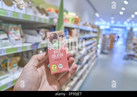 Hand holding dm pack of baked bread dm in a supermarket with blurred shelves in the background, buy organic product, buy organic, dmBio, retail, groce Stock Photo