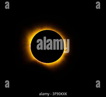 Solar eclipse glows against black sky. Crimson sunburst radiates around dark moon. Nature's cosmic spectacle, serene and powerful. Perfect for science Stock Photo