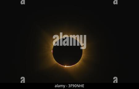 Stunning close-up capture of the solar corona and red prominences visible during the totality phase of a total solar eclipse. Detailed astronomical im Stock Photo