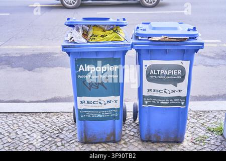 Two blue garbage cans of waste paper mistakenly filled with plastic bags Garbage contamination problem in garbage separation on the side of the road i Stock Photo