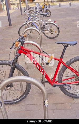 A red bicycle from the brand Canyon, bicycle frame, connected with bicycle lock in a bicycle rack on a paved walkway, anti-theft, Magdeburg, Saxony-An Stock Photo