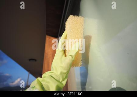 Cleaning a window with a sponge in bright daylight Stock Photo