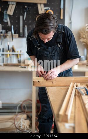 Woodworker precisely measuring wooden board replacement for vintage window frame at table. Stock Photo