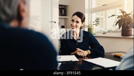 Happy, financial advisor and businesswoman with clients in office, talking or meeting with paperwork. Wealth management, retirement plan and Stock Photo