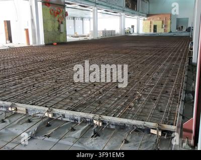 Extensive steel rebar grid prepared for pouring a concrete floor in a warehouse under construction Stock Photo