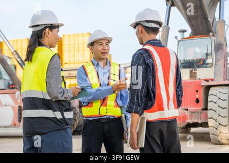 Construction team collaborating on project details at the job site for enhanced safety compliance. Ideal for business, teamwork, management, and const Stock Photo