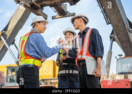 Construction personnel shaking hands after a successful project discussion in the shipping yard. Ideal for business, teamwork, construction, logistics Stock Photo