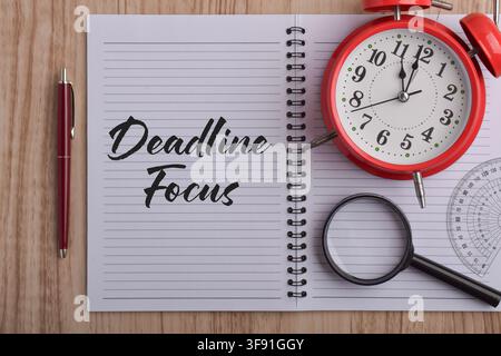 Deadline Focus text in a notebook with an alarm clock and magnifying glass, representing time management, productivity, prioritization Stock Photo