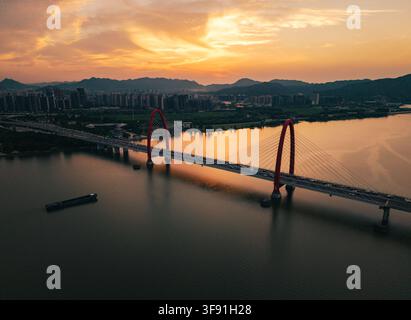 Sunset view of the Qiantang River showing the iconic red arches of the bridge in Hangzhou with traffic moving during a warm evening light Stock Photo