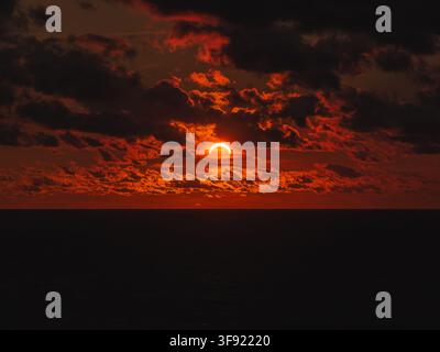 Solar eclipse during sunset with dark clouds over ocean horizon Stock Photo