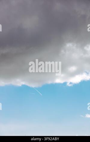 Airplane flying below ominous grey storm clouds Stock Photo