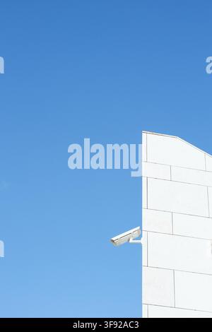 Security camera on modern building against blue sky Stock Photo
