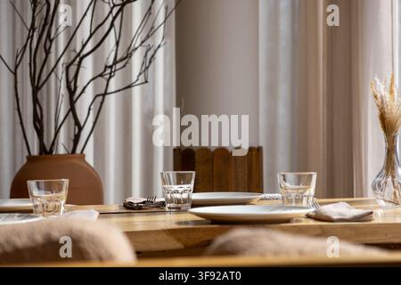 The minimalist dining setup features simple tableware on a light wood surface, reflecting a serene atmosphere for a modern home interior design that e Stock Photo