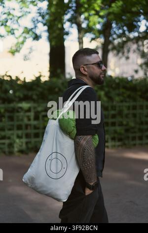Stylish tattooed man walking with a tote bag Stock Photo