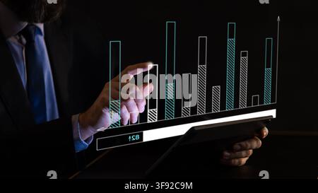 Businessman analyzing rising bar chart and performance data graphics on digital tablet Stock Photo