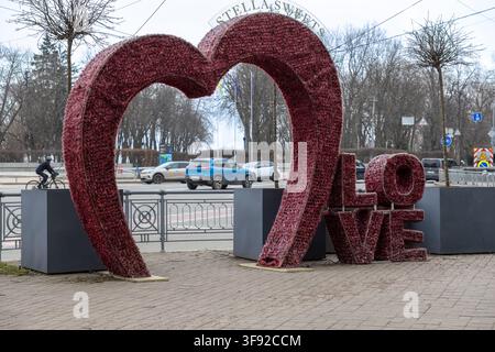 Kyiv, Ukraine - March 22, 2026: Stella Sweets decorative floral heart installation stands on a pedestrian path near a busy road, offering a charming b Stock Photo