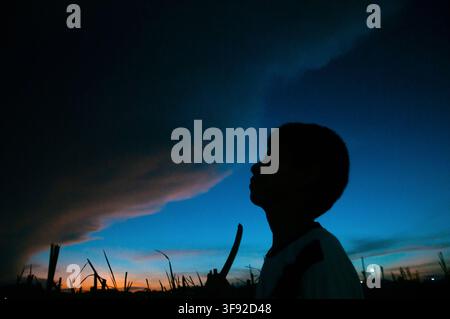 Silhouette of a boy watching a dramatic stormy sunset sky Stock Photo