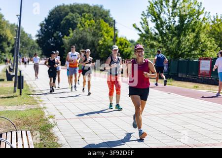 Smiling woman waves during a group run in the park Stock Photo