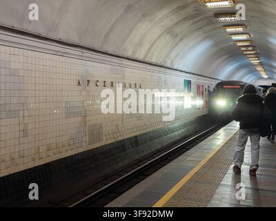 Kyiv, Ukraine - March 21, 2026: Commuter train pulling into the deep underground Arsenalna subway station where passengers stand on the platform, capt Stock Photo