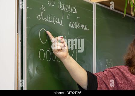 An educator explains complex mathematical symbols on a dark classroom board, guiding schoolchild development and supporting effective primary school p Stock Photo