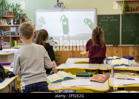 Primary school students observe a vibrant digital presentation during a classroom session, highlighting an interactive learning experience in a bright Stock Photo