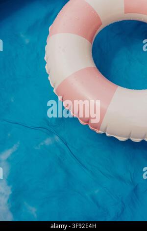 Pink striped inflatable ring floats in blue pool Stock Photo