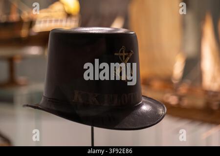 VIENNA, AUSTRIA, 13 August 2026: A black hat with an anchor emblem is displayed indoors against a softly blurred warm-toned background. Stock Photo