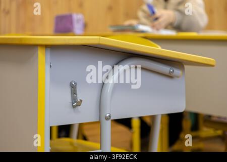 Close up of a wooden school desk with a metal hook in a primary classroom, capturing the quiet focus of students during lessons and the classic atmosp Stock Photo
