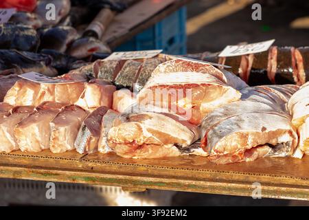 Sliced fish pieces arranged neatly on a wooden outdoor counter, capturing the authentic atmosphere of a traditional food market focused on fresh catch Stock Photo