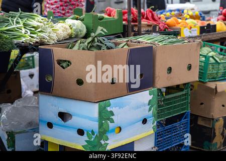 Assorted fresh seasonal produce inside stacked cardboard containers at an outdoor market stall, highlighting healthy nutrition and local agriculture i Stock Photo